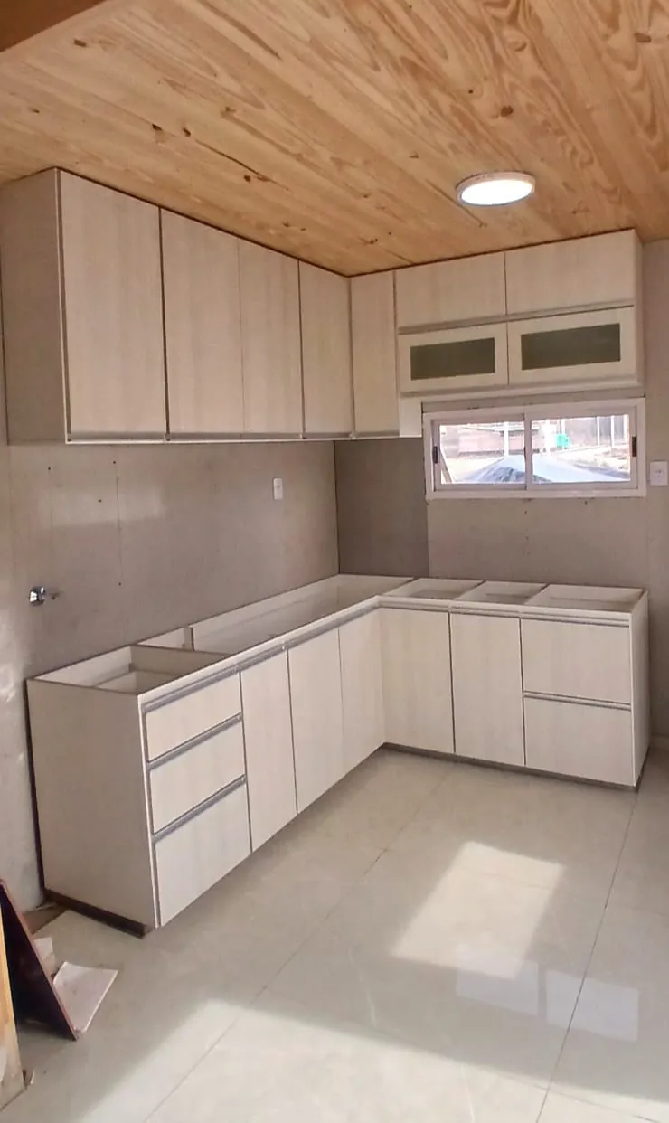 Cocina en L con bajomesada y alacenas claras, bajo un cielorraso de madera