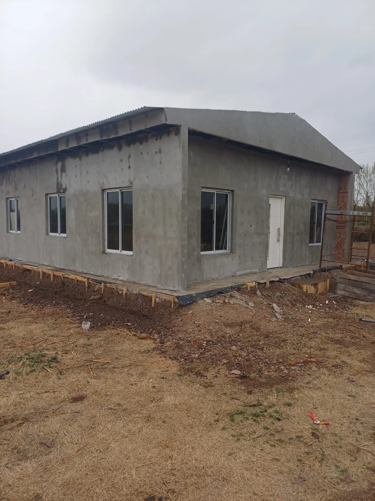 Vista de la casa con revoque gris y techo terminado