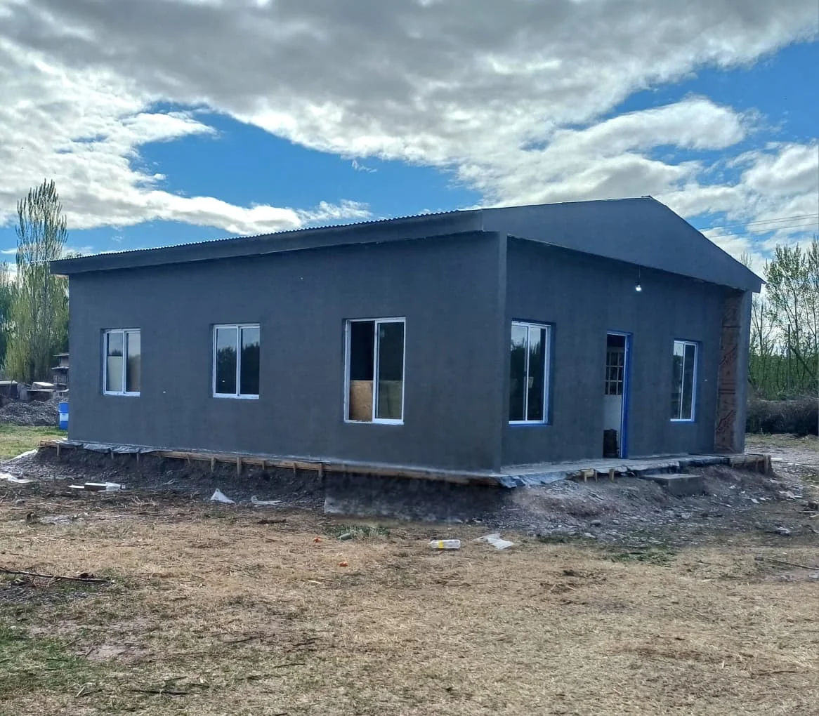 Casa construida por Foz con revoque gris, techo a dos aguas y aberturas blancas